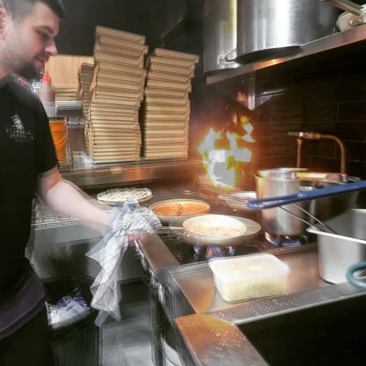 Our chef cooking pasta over a flaming stove in the kitchen
