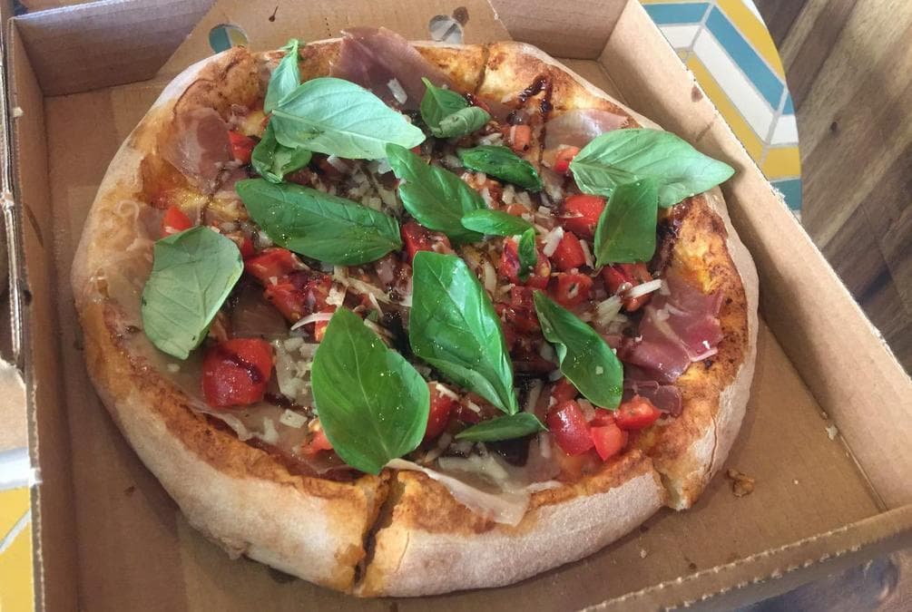 Prosciutto pizza with tomato, basil and rocket